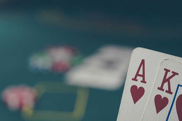 Eine Hand hebt zwei Spielkarten auf einem Pokertisch leicht an